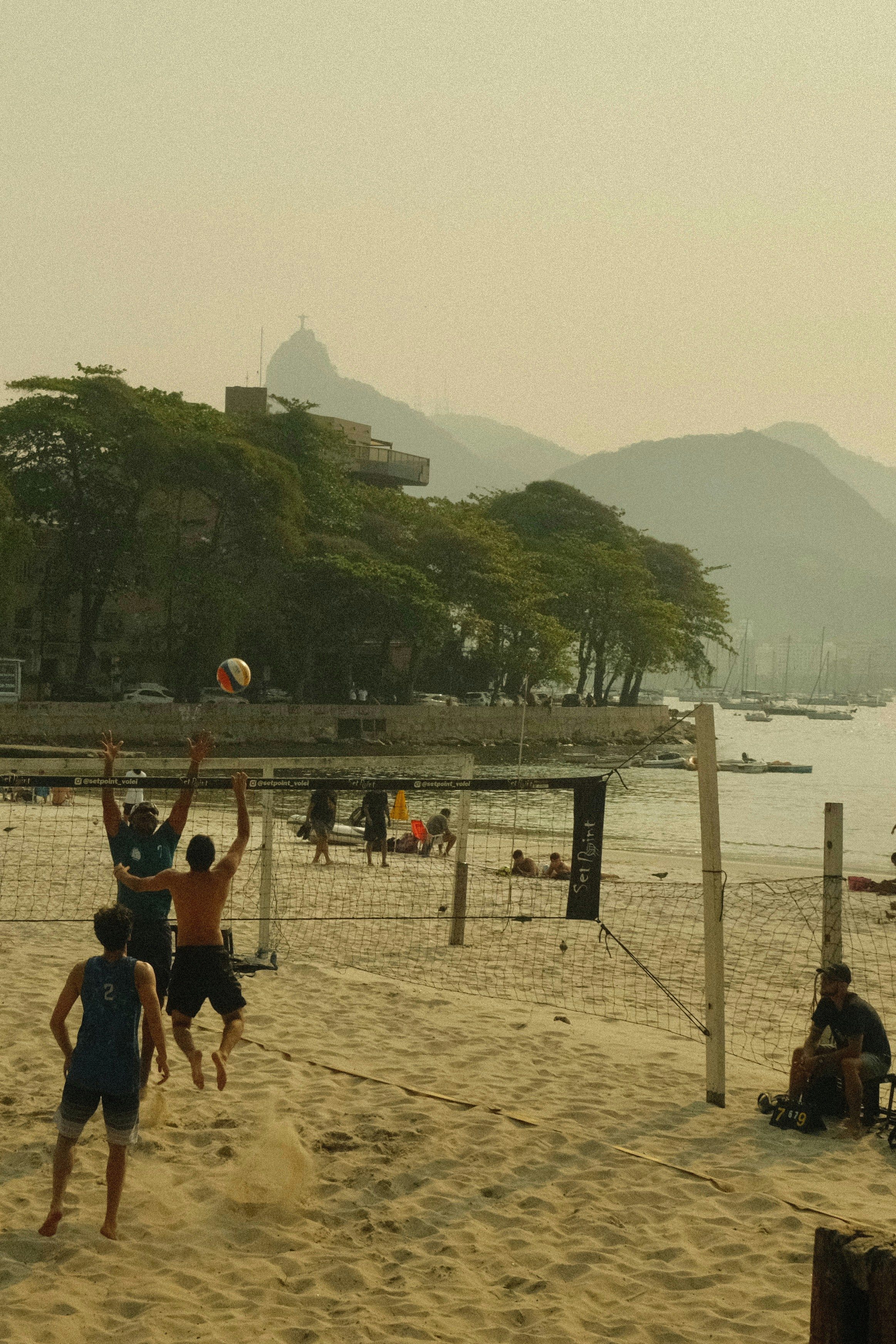 Beach volleyball game on the sand in Rio de Janeiro, Christ the Redeemer in the distance.