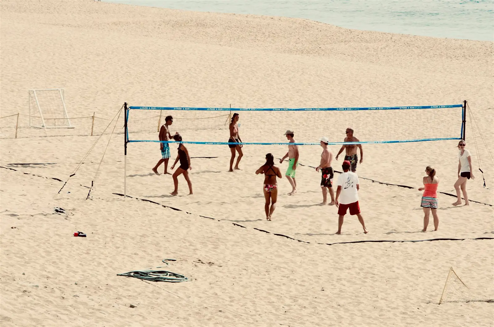 Towarzyski mecz siatkówki plażowej na szerokiej, piaszczystej plaży nad morzem.