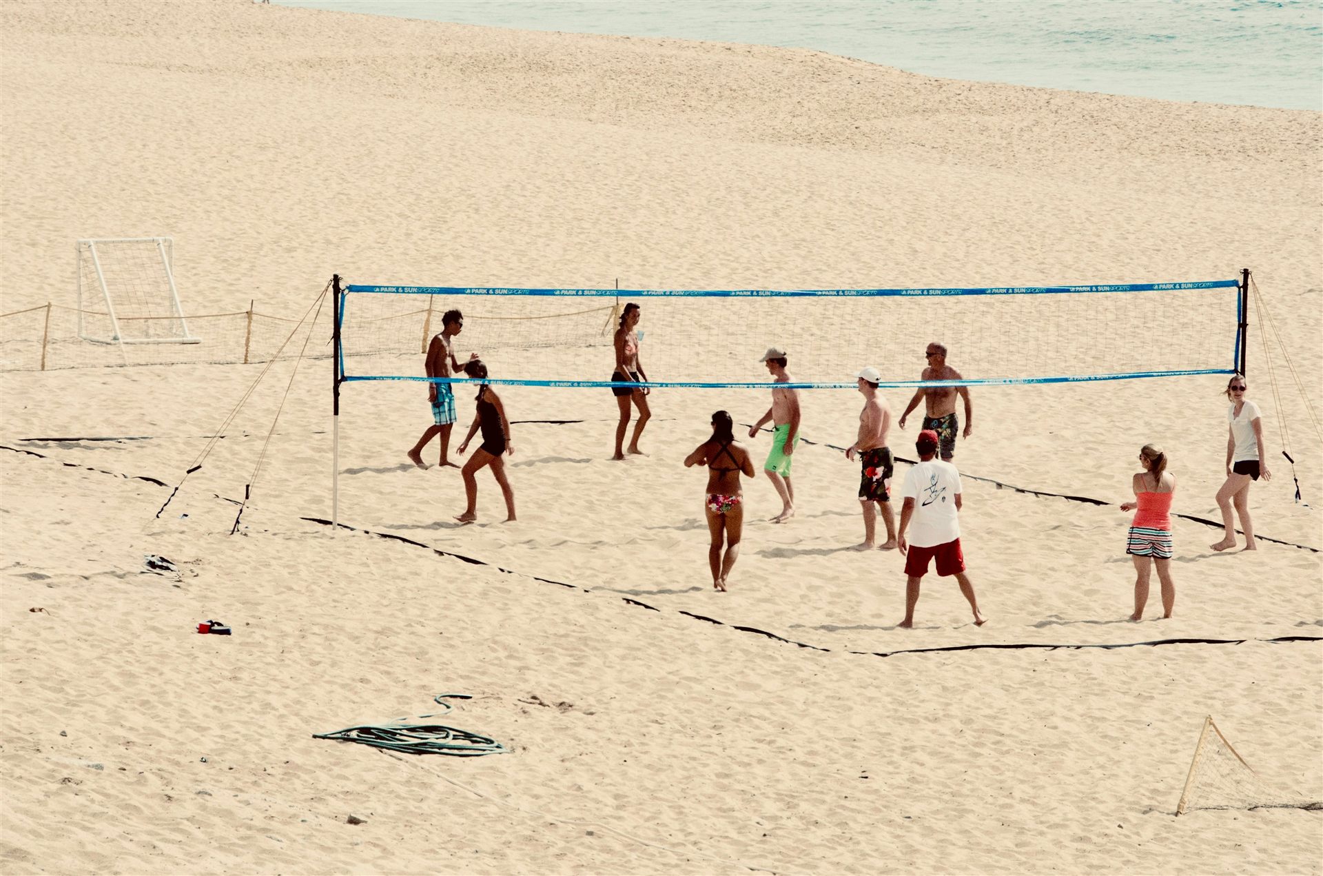 Friendly beach volleyball game on a wide sandy beach by the sea.