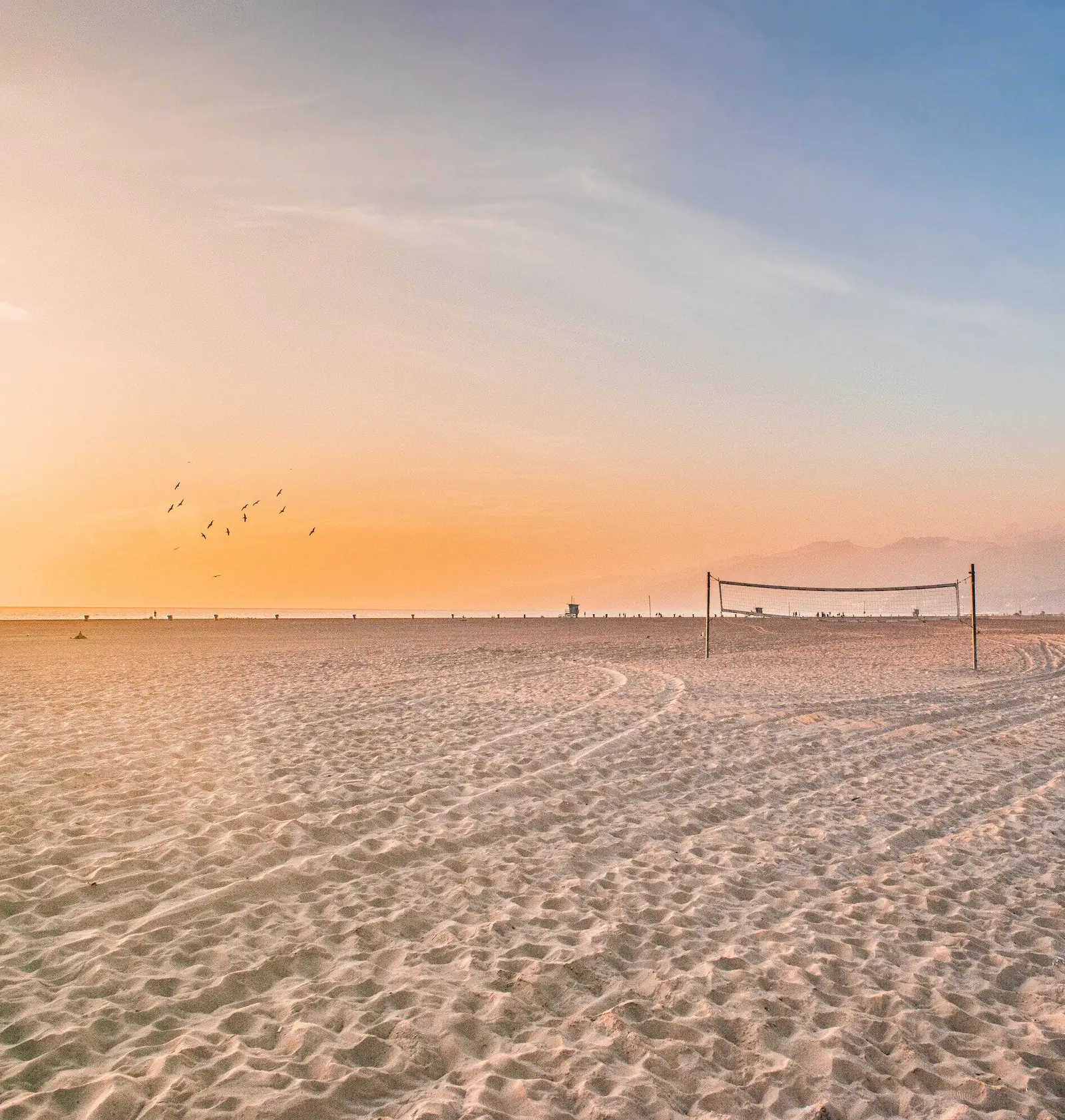 Boisko do siatkówki plażowej na piasku nad morzem o zachodzie słońca.